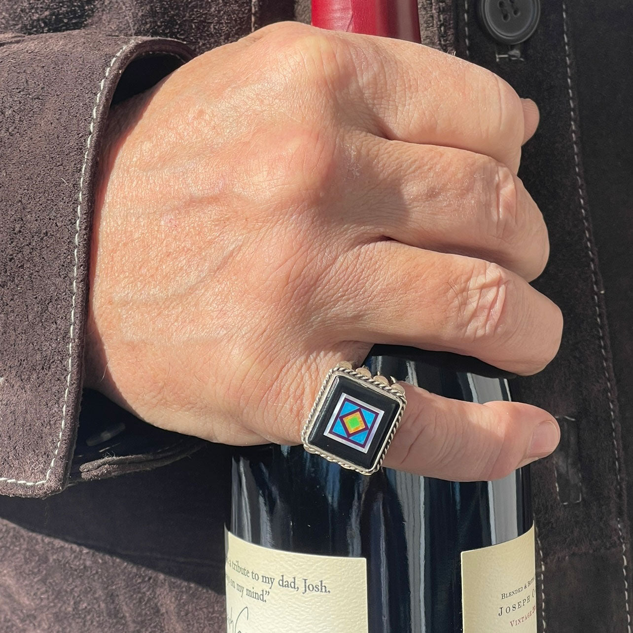 man wearing a sterling silver jet inlay ring by aldrich art jewelry on his pinkie finger