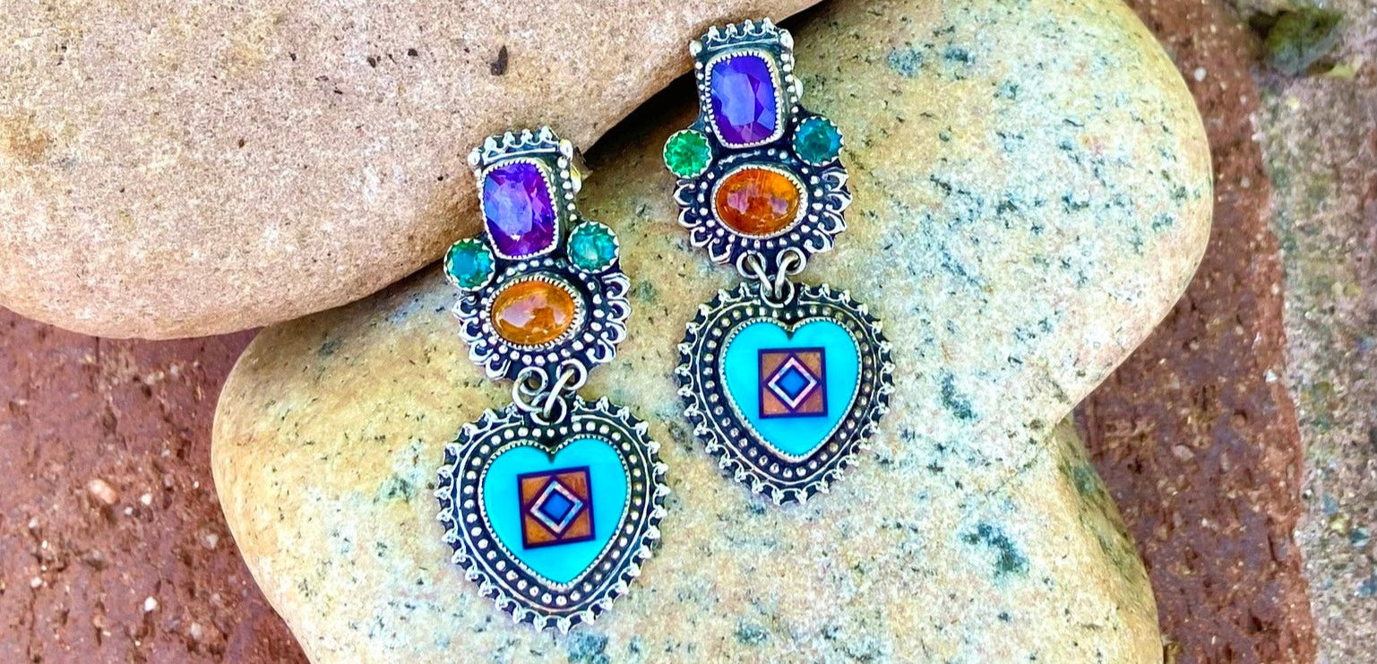 turquoise heart inlay with amethyst and carnelian gemstone earrings by aldrich art jewelry resting on river stones