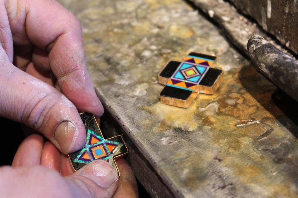 bench jeweler at aldrich art jewelry fitting a cross shaped inlay stone into a sterling silver bezel