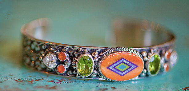 aldrich art jewelry sterling silver bracelet featuring a center stone of hand-inlay orange spiney oyster, opal, sugilite, and orville jack turquoise with faceted peridot, carnelian and white topaz accents